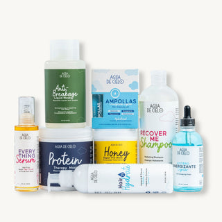 The best hair treatment for damaged hair from the brand Agua DE Cielo, arranged neatly on a clean off-white background. The products include various bottles, jars, and boxes in different colors (green, blue, yellow, white, and navy) with labels such as 'Anti Breakage', 'Protein Therapy Moisture', 'Honey', 'Recover Me Shampoo', 'Hair Hydrate', and 'Everything Serum'.