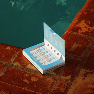 Hair Ampoules Set sits open on a tiled poolside surface with swimming pool water in the background.