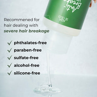 A bottle of Agua de Cielo hair breakage treatment is tilted to pour a clear gel-like product into a glass. The bottle has a green label with white text.