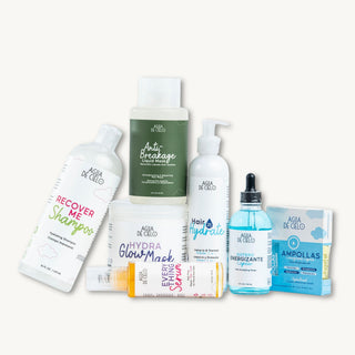 A hair hydration treatment from Agua de Cielo arranged on a plain off-white background. The products include a white bottle of Recover Me Shampoo, a green bottle of Anti Breakage Treatment, a white pump bottle of Hair Hydrate, a white jar of Glow Mask Serum, a blue dropper bottle of Osmotic Emulsion, and a blue packet of Ampollas.