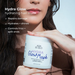 A close-up of a woman holding a white jar of Agua de Cielo Hydra Glow Mask for hair recovery kit, with promotional text on the left highlighting hair repair and hydration benefits.