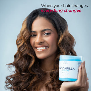 A smiling woman with long, wavy brown hair holds a light blue and white jar labeled 'nourishing hair mask for dry hair by agua de cielo' against a soft light blue background. Text at the top reads, 'When your hair changes, everything changes.
